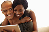 Couple using tablet computer on sofa