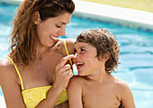 Mother applying sunscreen to son's face