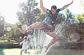 Father and son playing in sprinkler