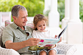 Older man reading to granddaughter