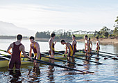 Rowing team placing boat on lake