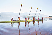 Rowing team with oars raised on lake