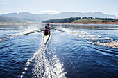 Rowing crew rowing scull on lake