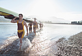 Rowing crew carrying scull out of lake