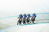 Track cyclists riding in velodrome