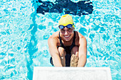 Smiling swimmer poised at starting block