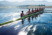 Rowing team rowing scull on lake