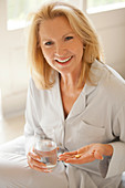 Woman holding pill and glass of water