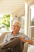 Smiling senior man using tablet on porch
