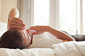 Man laying in bed with head in hands
