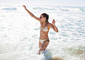 Enthusiastic woman splashing in ocean