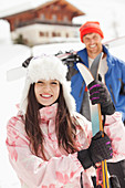 Smiling couple with skis outside cabin