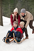 Happy family sledding in snowy woods