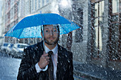 Businessman with tiny umbrella in rain