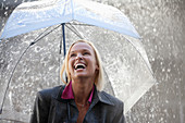 Laughing businesswoman under umbrella