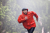 Man in raincoat running in rain