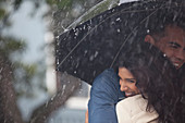 Happy couple hugging under umbrella