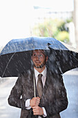 Businessman under umbrella in rain
