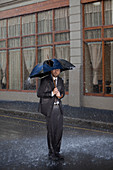 Businessman under broken umbrella