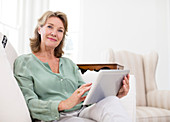 Senior woman using tablet on sofa