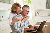 Senior couple using laptop in kitchen