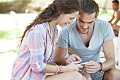 Couple listening to mp3 player outdoors