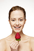 Smiling woman eating strawberry