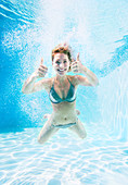 Woman giving thumbs up underwater
