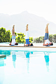 Men and woman practicing yoga poolside