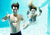 Couple giving thumbs up underwater