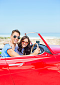 Couple driving convertible at beach