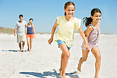 Girls holding hands and running on beach