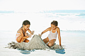 Girls building sandcastle on beach