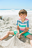 Boy building sandcastle on beach