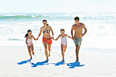Family holding hands and running on beach