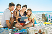 Family using digital tablet on beach