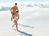Father and daughter running in surf