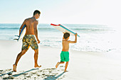 Father and son carrying surfboard