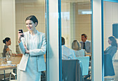Businesswoman using cell phone in meeting