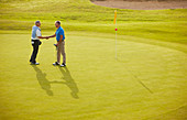 Senior men shaking hands on golf course