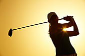 Silhouette of woman playing golf