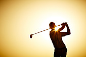 Silhouette of man swinging golf club