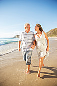 Senior couple walking in surf on beach