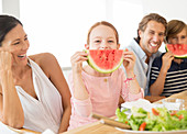 Family eating watermelon at table