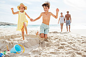 Children kicking down sandcastle on beach