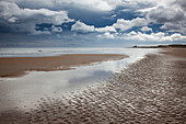 Clouds over beach at low tide