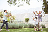 Family playing volleyball in backyard