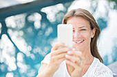 Woman holding cell phone at poolside