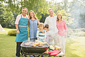 Family standing at barbecue in backyard
