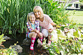 Grandmother and granddaughter by pond